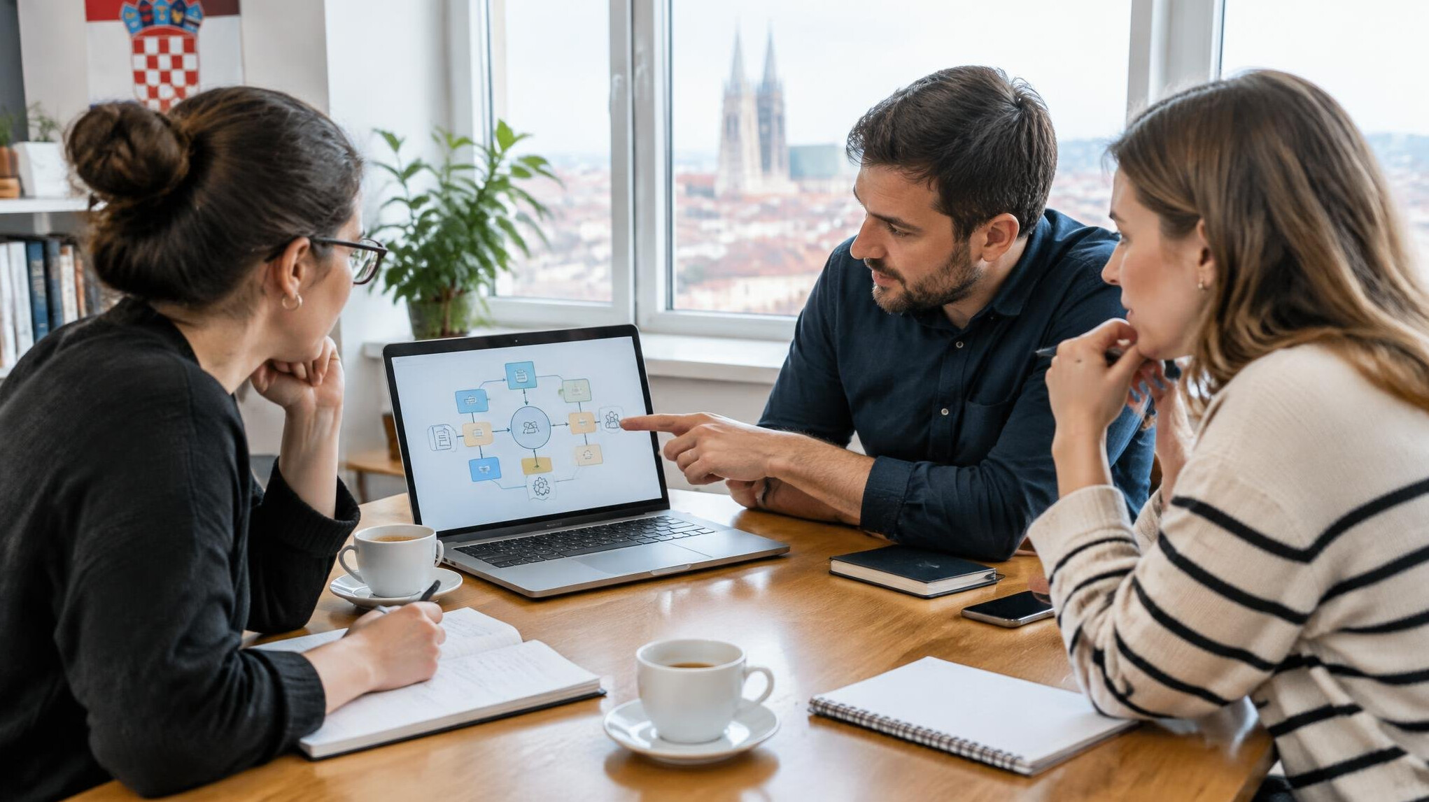 Small group gathered around a table discussing a diagram on a laptop screen